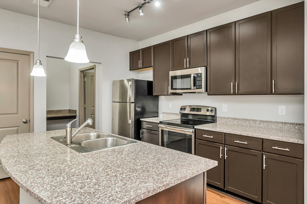 A kitchen with brown cabinets and granite countertops.